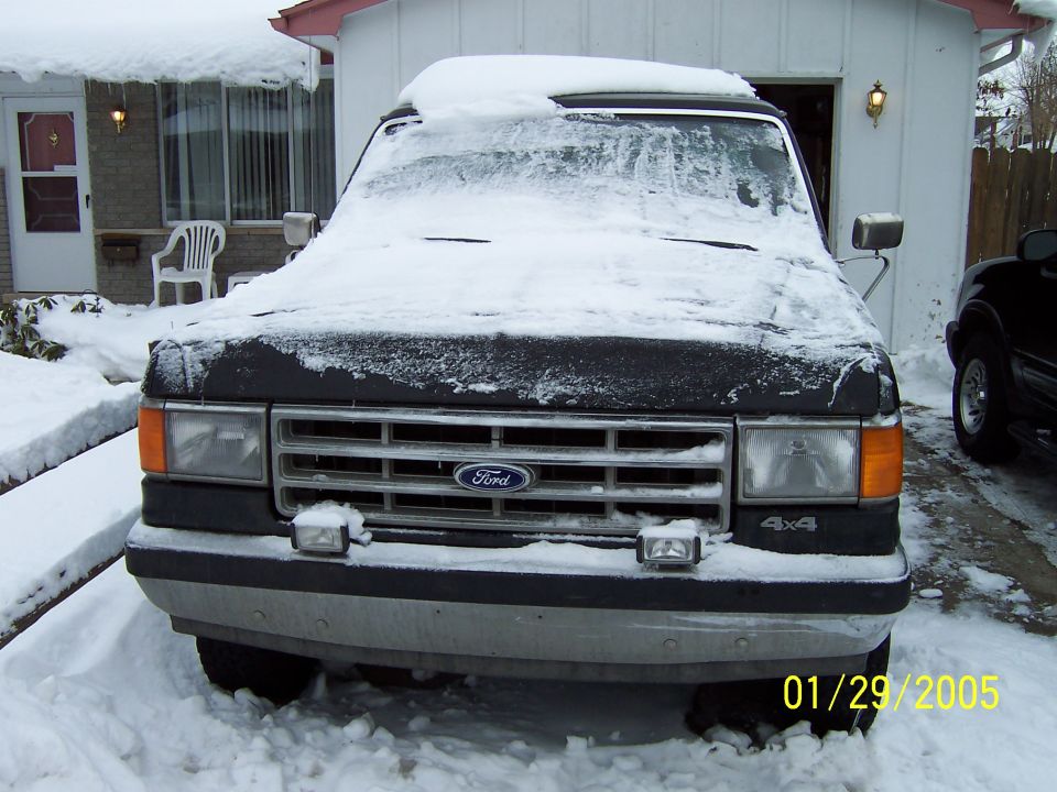 Ford Bronco covered in snow, front view. Has 4x4 badge