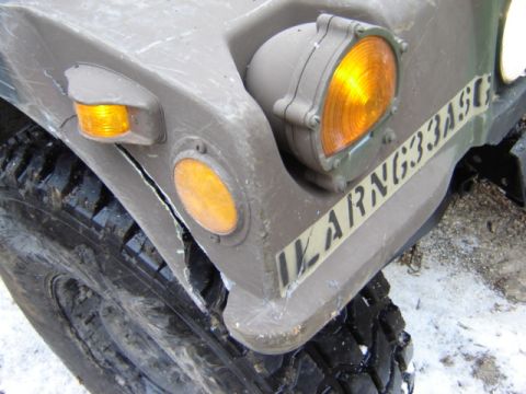 1992 Ford Bronco - Close-up of a military vehicle's front corner, showing damage and markings.