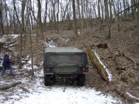 1992 Ford Bronco - A camouflaged military vehicle navigates a snowy, wooded terrain during what appears to be an off-road excursion.