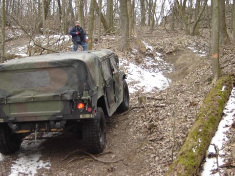 1992 Ford Bronco - A military vehicle navigates a wooded trail during a snowy day.