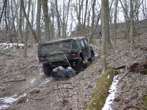 1992 Ford Bronco - A military truck navigates a challenging off-road course through a dense forest.