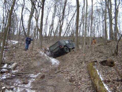 1992 Ford Bronco - A military vehicle navigates a challenging off-road course through a dense forest.