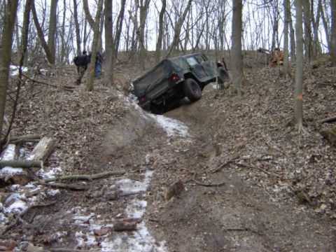 1992 Ford Bronco - Off-road vehicle navigating a challenging, muddy terrain in a wooded area.