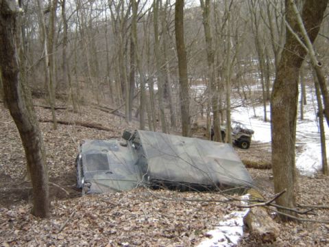 1992 Ford Bronco - Two off-road vehicles are visible in a wooded area, one appears stuck and covered.