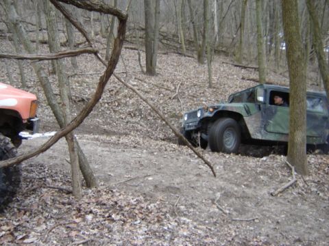 1992 Ford Bronco - Two vehicles navigate a wooded trail with fallen leaves covering the ground.
