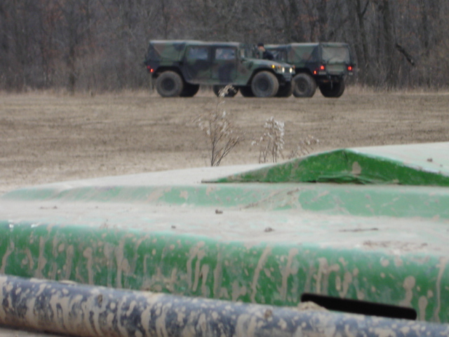 Two camouflage military vehicles parked in a field