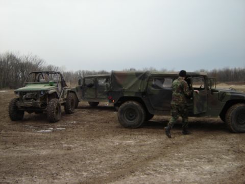 1992 Ford Bronco - A soldier enters a camouflage Humvee while another Humvee and an off-road vehicle are parked nearby.
