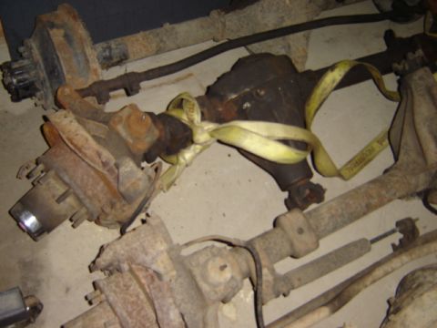 1992 Ford Bronco - Multiple rusty vehicle axles and suspension parts are shown on the floor.
