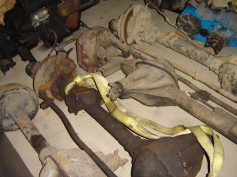 1992 Ford Bronco - A collection of used vehicle axles are stored indoors, showing signs of rust and wear.