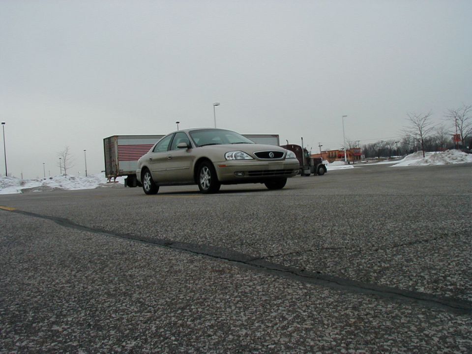 Tan Mercury Sable parked in a lot with a semi-truck behind it
