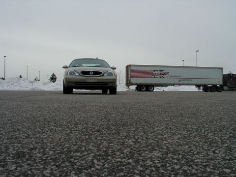 2001 Mercury Sable - A tan Mercury Sable is parked in front of a semi-trailer truck on a cloudy day.