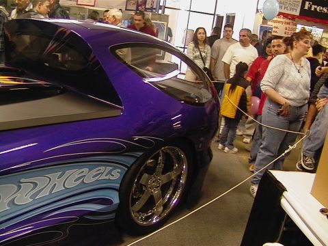 1999 Ford Taurus - A custom purple car with "Hot Wheels" graphics is displayed indoors, with spectators in the background.