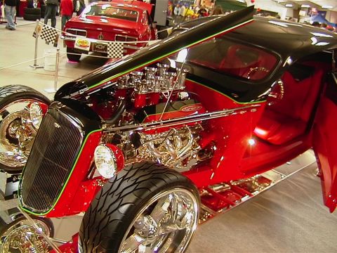 1999 Ford Taurus - A custom hot rod with a powerful engine is displayed indoors, with another red car in the background.
