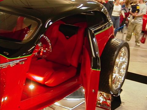 1999 Ford Taurus - A custom hot rod with a striking red interior and black exterior is displayed at a car show.