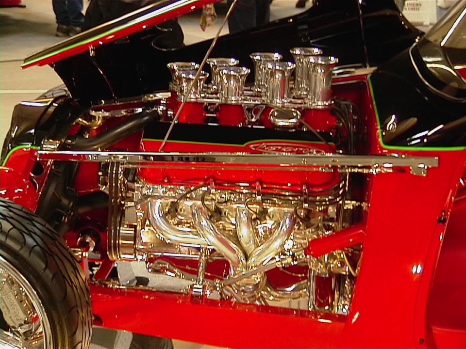 Close-up of a polished V8 engine with chrome headers and multiple carburetors