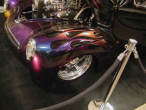 1999 Ford Taurus - A custom hot rod with a vibrant flame paint job and chrome accents is displayed indoors.