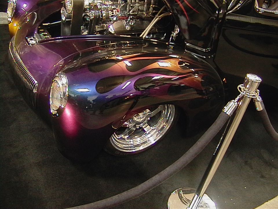 Custom hot rod with purple and blue flame paint job, chrome wheels, and exposed engine