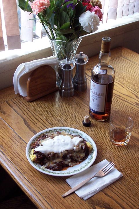 1990 Ford Bronco - A meal is served with a bottle of Macallan 18 Year Old Scotch Whisky and a glass, alongside a plate of food and a bouquet of flowers.