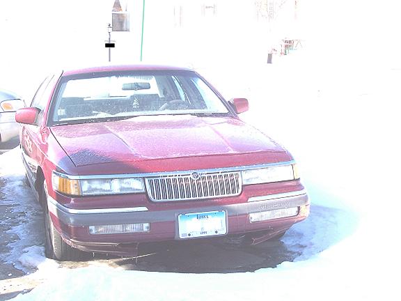 Maroon Mercury Grand Marquis front end with frost on hood, Iowa plate, parked on snowy lot