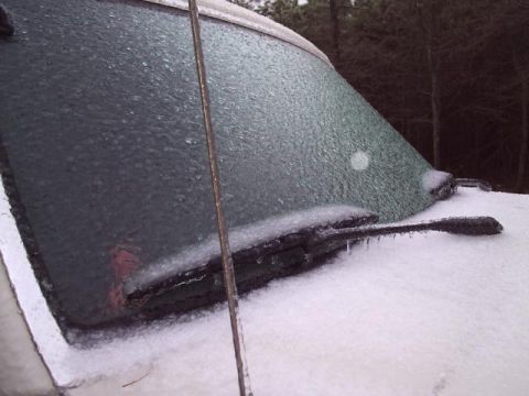 1989 Ford Bronco - A vehicle's windshield and wipers are covered in ice and snow, indicating harsh winter conditions.