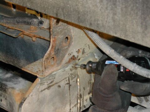 1994 Ford Bronco - A Dremel tool is used to modify the rusty frame of a vehicle, likely for custom work.