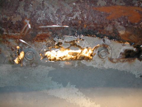 1994 Ford Bronco - Close-up view of rusted metal with visible bolts, likely a vehicle part.