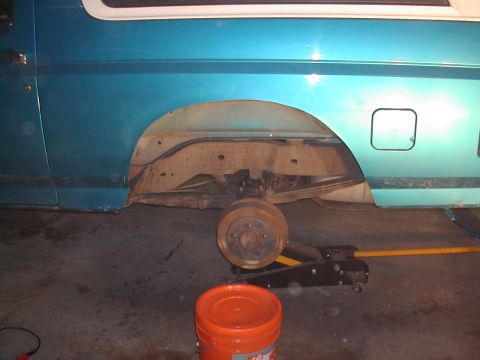 1994 Ford Bronco - Rear wheel well of a teal 1994 Ford Bronco, showing suspension components with the wheel off.