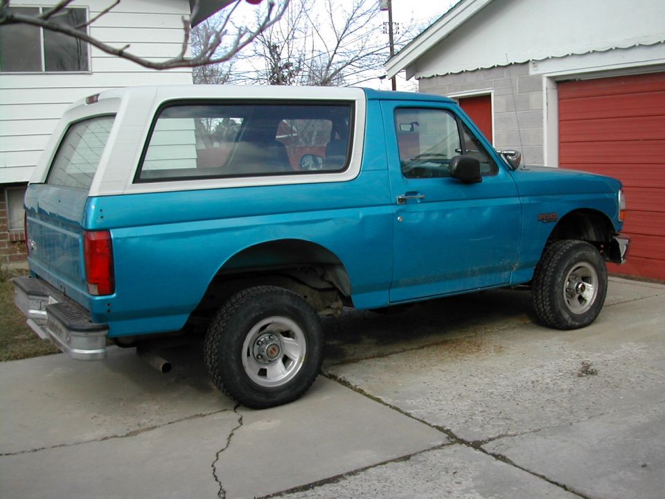 1994 Ford Bronco, blue with white removable top, parked on concrete driveway