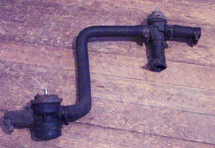 Black metal hose assembly with two valves, one on each end, against a wooden background