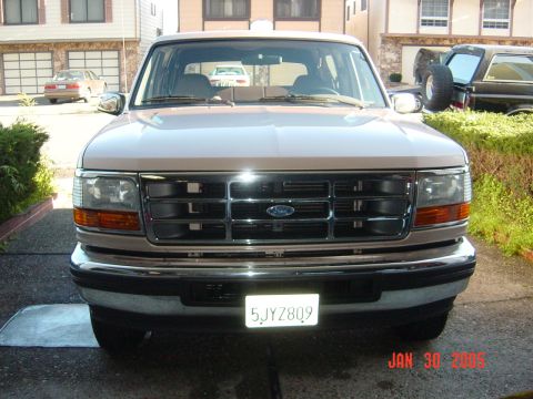 1990 Ford Bronco - A tan Ford Bronco is parked in a driveway, with another vehicle visible to the right.