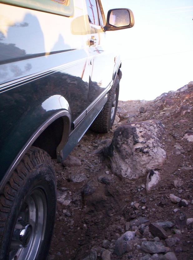 1996 Ford Bronco driving over rocks on a trail, side view
