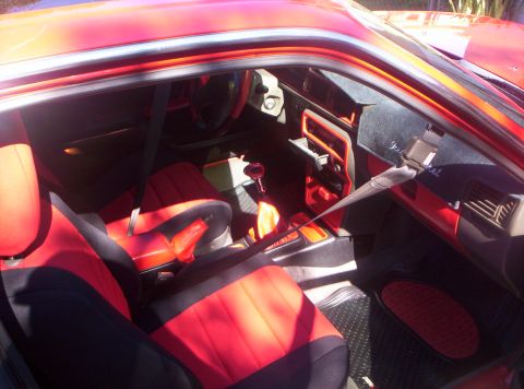 1991 Mazda MX-6 - The interior of a red car features two-tone black and red seats, a manual gear shifter, and a dashboard with visible vents.