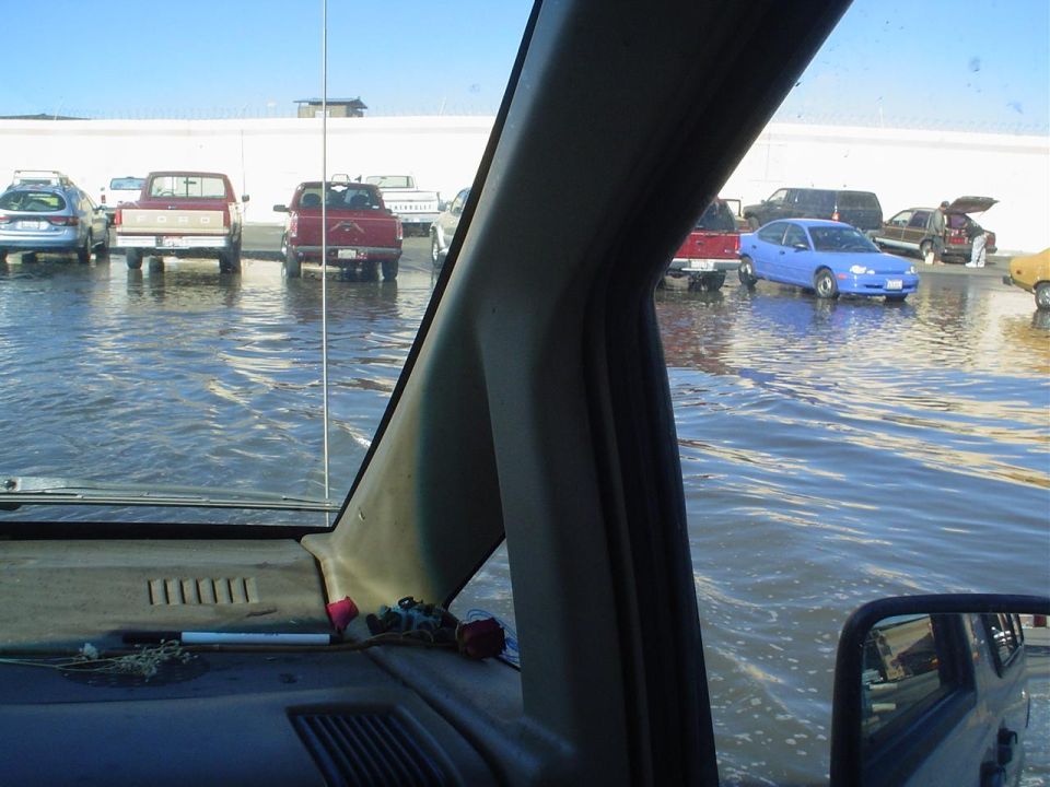 Cars and trucks parked in a flooded lot under a clear sky
