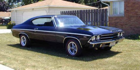 1990 Ford Taurus - A classic black 1969 Chevrolet Chevelle coupe is seen from a three-quarter front view, parked on a grassy lawn in front of a garage.