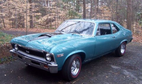 1990 Ford Taurus - A teal 1969 Chevrolet Nova SS sits on a driveway surrounded by trees.