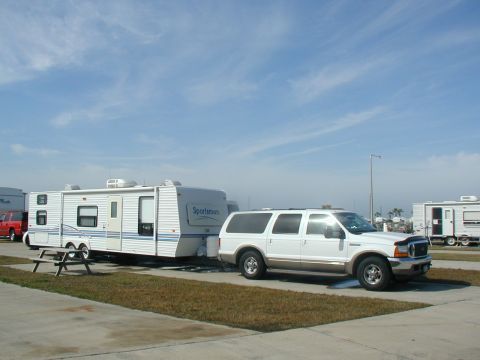 2000 Ford Excursion - A white 2000 Ford Excursion is parked and towing a travel trailer at a campsite.