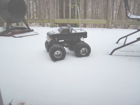 1986 Ford Bronco - A toy monster truck sits in the snow on a wooden deck, with a large heater in the background.