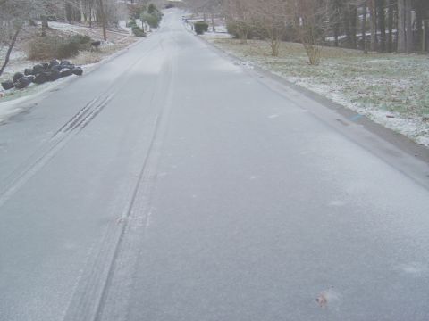1986 Ford Bronco - A residential street covered in ice and snow, showing tire tracks from a vehicle.