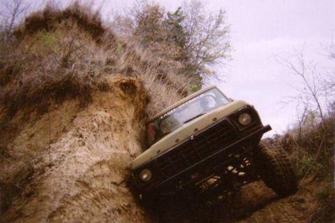 1978 Ford Bronco - A tan 1978 Ford Bronco navigates a steep dirt incline, its off-road capabilities.