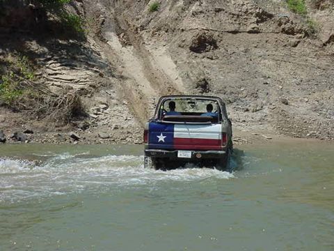 1978 Ford Bronco - This vehicle is navigating a water crossing with a steep dirt bank in the background.