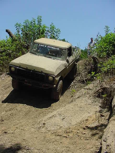 1978 Ford Bronco - A man stands in the background as a vintage Ford truck navigates a steep, muddy incline.