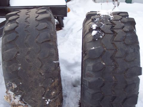 1974 Ford Bronco - Two large off-road tires are shown in a snowy environment, with one tire appearing slightly larger than the other.
