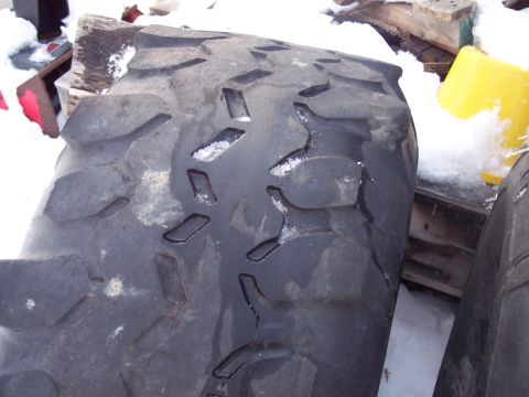 1974 Ford Bronco - A close-up view of a large tire, likely for an off-road vehicle, with snow accumulated in its aggressive tread pattern.