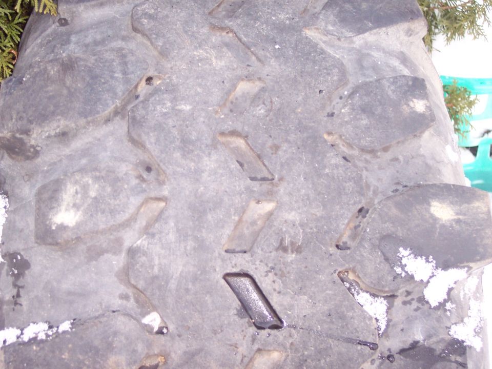 close-up of a large, knobby tire tread with some snow on it