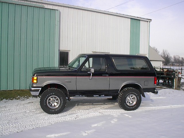 Side view of a 1989 Ford Bronco in black and grey with off-road tires