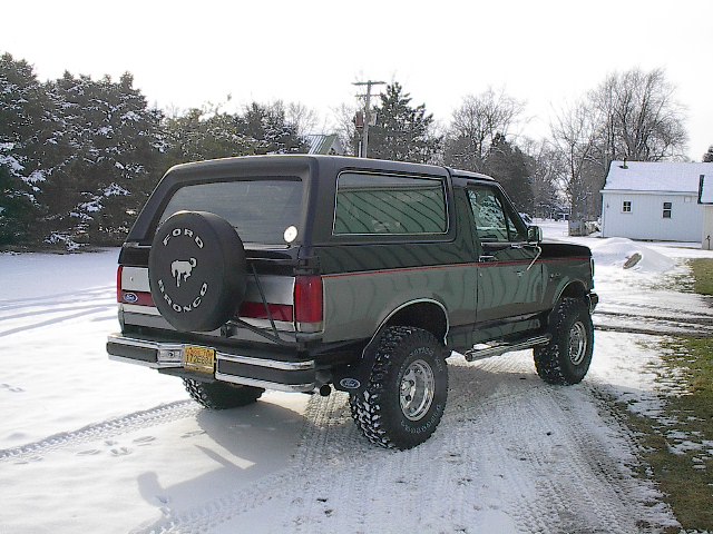 Ford Bronco parked in snow, spare tire on back. License plate visible