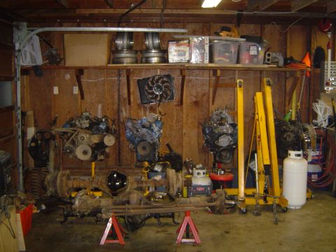 1989 Ford Bronco - Garage scene with multiple engines and axles, suggesting a workshop or restoration area.