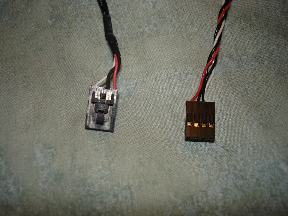 Two electrical connectors with red, black, and white wires against a textured background. One connector is gray with a black latch, the other is brown with gold pins
