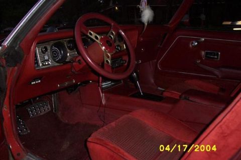 1979 Pontiac Firebird - The interior of a classic car features red upholstery, a custom steering wheel, and a detailed dashboard.