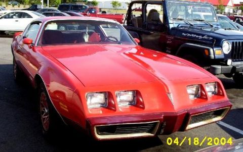 1979 Pontiac Firebird - A red Pontiac Firebird is parked next to a blue Jeep Wrangler.